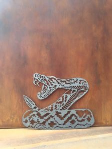 coiled rattle snake about to strike raw steel with a rusted steel background